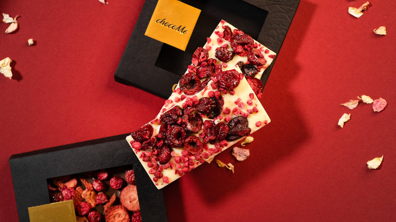 Weiße Schokolade mit Sauerkirschen und Preiselbeeren von ChocoMe mit rotem Hintergrund und Deko Mood Picture