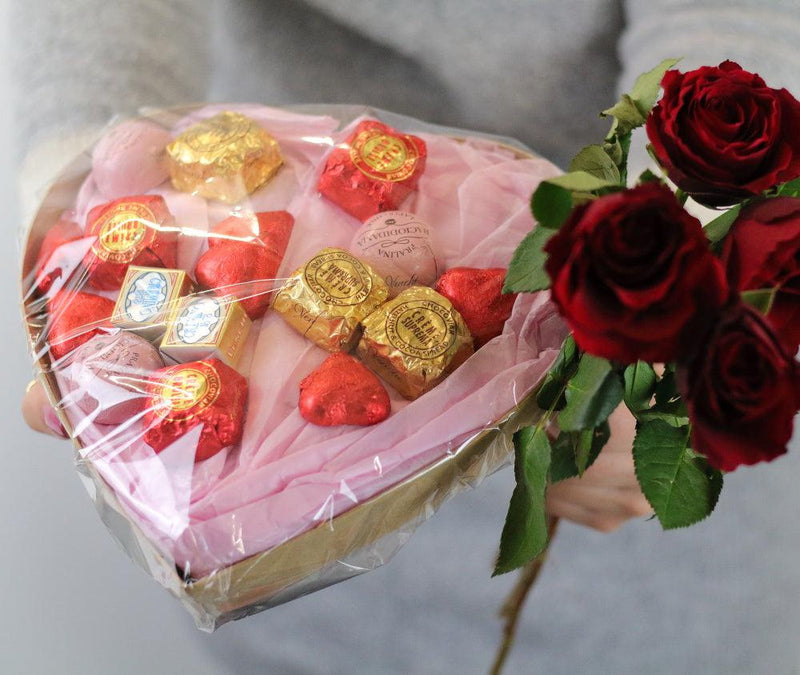 Herzenkorb gefüllt mit unterschiedlichen Pralinen von Venchi mit einem Strauß roter Rosen