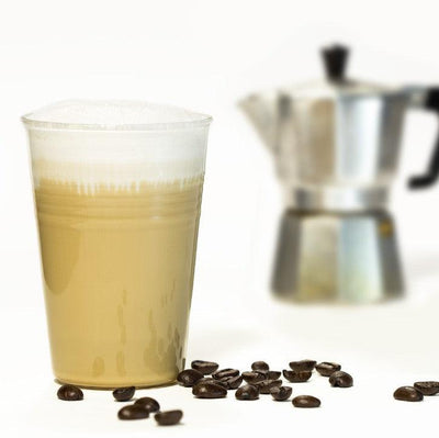 Latte-Macchiato im Glas neben Kaffeemaschine und Kaffebohnen 