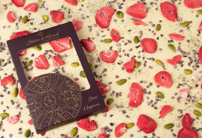 Weiße Schokolade mit Erdbeeren im ganzen Bild und auf der linken Seite eine Tafelschokolade